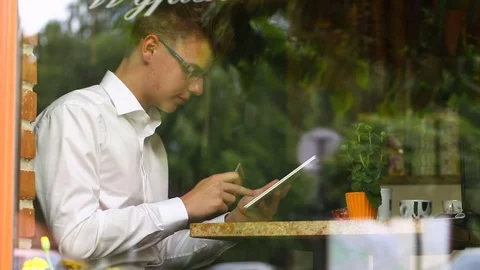 Businessman sitting behind cafe's window and doing online shopping Stock Footage 80425026