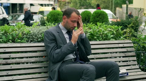 Businessman sitting on the bench and having headache Stock Footage 43125859