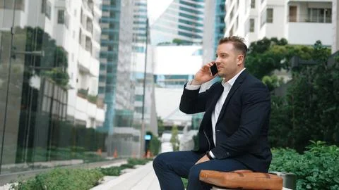 Businessman sitting at bench while talking to manager by using phone. Urbane. 스톡 사진