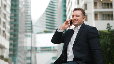 Businessman sitting at bench while talking to manager by using phone. Urbane. Foto stock