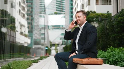 Businessman sitting at bench while talking to manager by using phone. Urbane. 스톡 사진