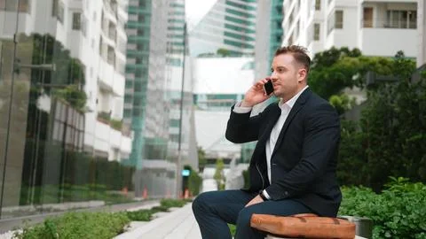 Businessman sitting at bench while talking to manager by using phone. Urbane. Stock Photos