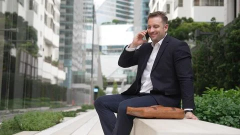 Businessman sitting at bench while talking to manager by using phone. Urbane. 스톡 사진