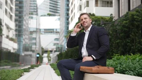 Businessman sitting at bench while talking to manager by using phone. Urbane. 스톡 사진