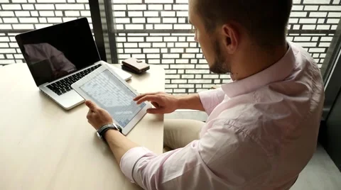 Businessman sitting in cafe with laptop, using tablet pc. Indoor photo. Stock Footage 55653732