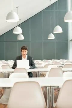 Businessman sitting at a cafeteria and using a laptop Stock Photos