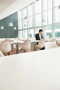 Businessman sitting at a cafeteria and using a laptop Stock Photos
