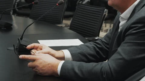Businessman sitting at conference table with microphone during meeting. Stockbeeldmateriaal 320885642