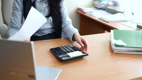 Businessman sitting at desk, he is using a calculator and checking Stock Footage 334628158