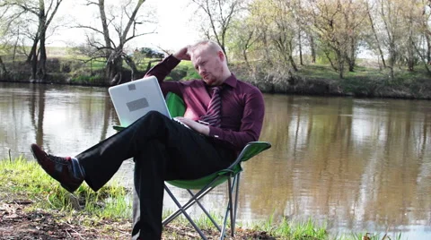 Businessman Sitting Sad With a Tablet and is Forced to Work For Camping by the Stock Footage 62777029