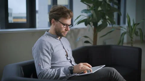 Businessman Sitting On Sofa In Office Using Digital Tablet Stock Footage 68676272