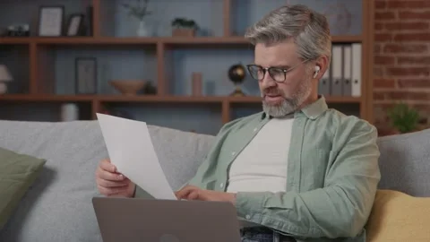 Businessman sitting on sofa working remotely with pleasure hold documents Vídeos de archivo 220201433