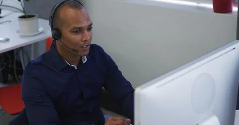 Businessman sitting using computers talking with phone headsets 스톡 사진