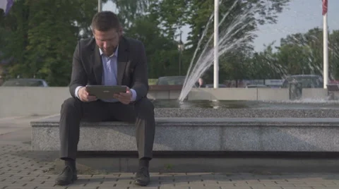Businessman sitting on wall, browsing tablet. Vídeo Stock 52754849