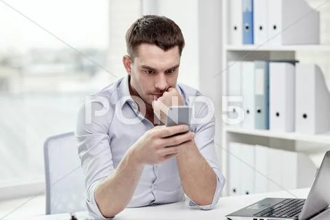 Businessman with smartphone and laptop at office Stock Photos