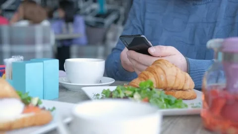 Businessman with smartphone while having lunch in a cafe. Close view of 스톡 동영상 240123855