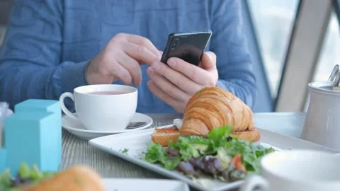 Businessman with smartphone while having lunch in a cafe. Close view of Video stock 240320146