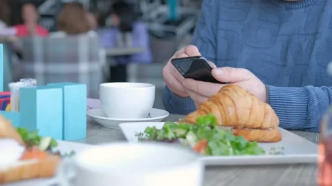 Businessman with smartphone while having lunch in a cafe. Close view of Stock Footage 240320326