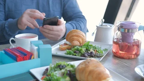 Businessman with smartphone while having lunch in a cafe. Close view of Stock Footage 240477701