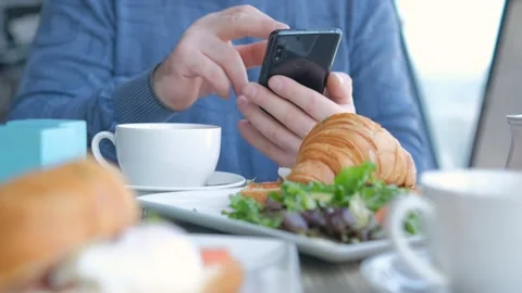 Businessman with smartphone while having lunch in a cafe. Close view of Stock Footage 240974267