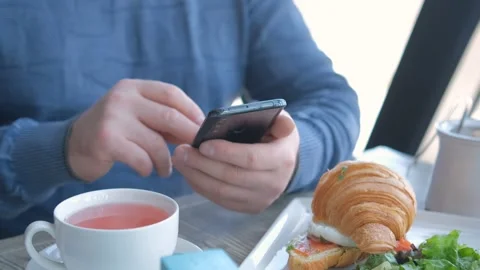 Businessman with smartphone while having lunch in a cafe. Close view of Stock Footage 241129909