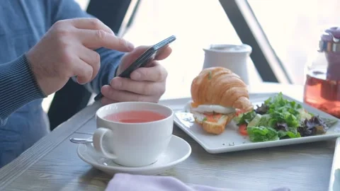 Businessman with smartphone while having lunch in a cafe. Close view of Stock Footage 241343304