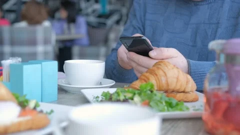 Businessman with smartphone while having lunch in a cafe. Close view of Stock-Footage 241518616