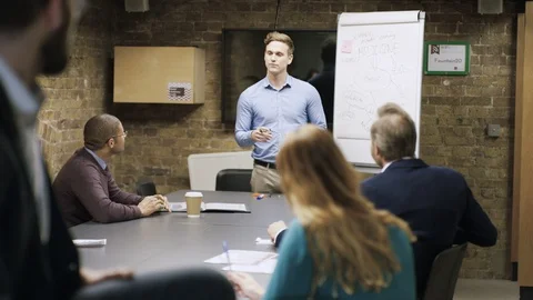 Businessman smiling at camera while colleagues have a meeting in background Stock Footage 107888816