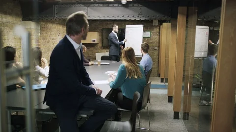 Businessman smiling at camera while colleagues have a meeting in background Stock Footage 107889031