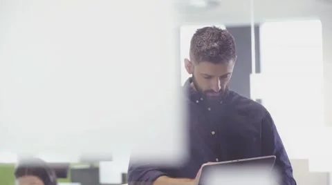 Businessman smiling to camera whilst using tablet in the office Stock Footage 67345350