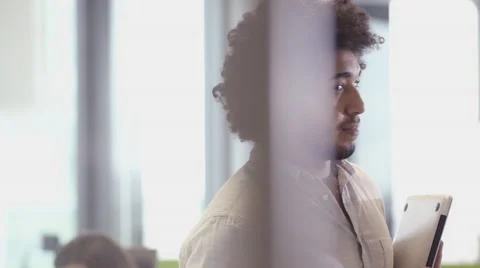 Businessman smiling to camera whilst using tablet in the office Stock Footage 67386369