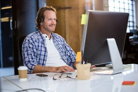 Businessman smiling while using computer at desk in creative office Foto stock