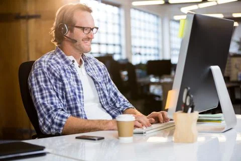 Businessman smiling while working on computer at desk in creative office Foto stock