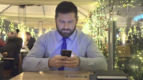 Businessman sms typing using smartphone app, evening, cafe, portriat, christmas Vidéo 72999561