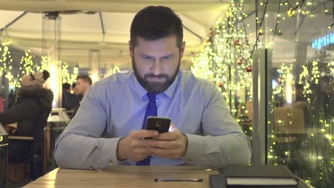 Businessman sms typing using smartphone app, looking ato camera, evening, cafe Vídeo Stock 72999623