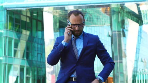 Businessman speaking on cellphone and checking time on wristawatch, steadycam sh Stock Footage 97165722