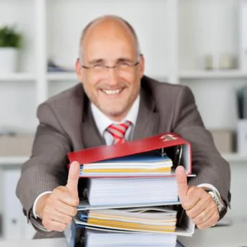 Businessman with stack of books gesturing thumbs up 스톡 사진