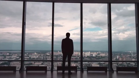 The businessman stand near the panoramic window on the morning city background Stock Footage 80512034