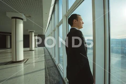 The businessman stand near panoramic window Stock Photos