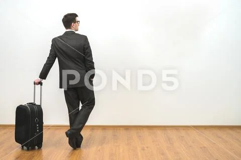 The businessman standing with a bag on the white wall background Stock Photos