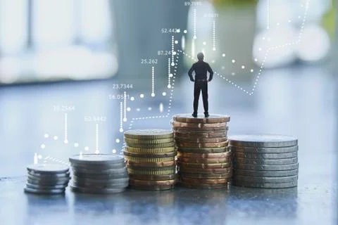Businessman standing on coins stack with graph chart Stock Photos