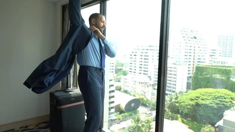 Businessman standing in front of the window and puts his jacket on, slow motion  Stock Footage 88532834