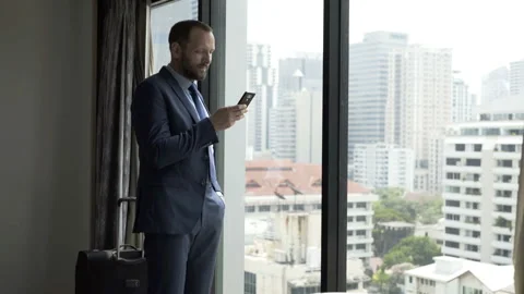 Businessman standing in his apartment and browsing internet on smartphone Stock Footage 88530153