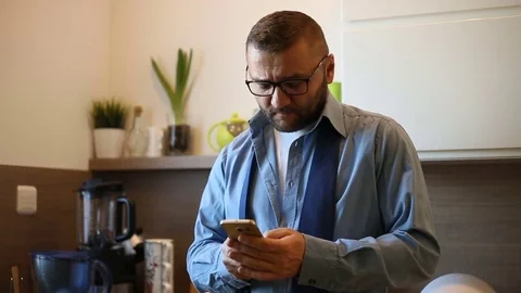 Businessman standing in the kitchen at the morning and using smartphone Stock Footage 73503953