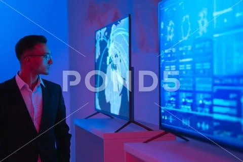 The businessman standing near screens in the dark room Stock Photos