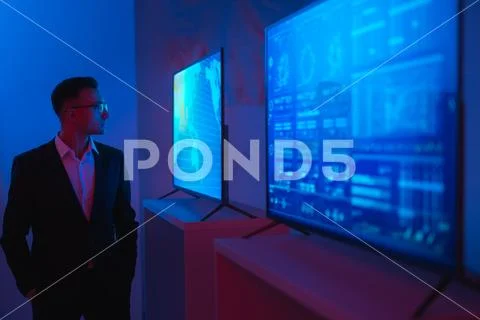 The businessman standing near screens in the dark room Stock Photos