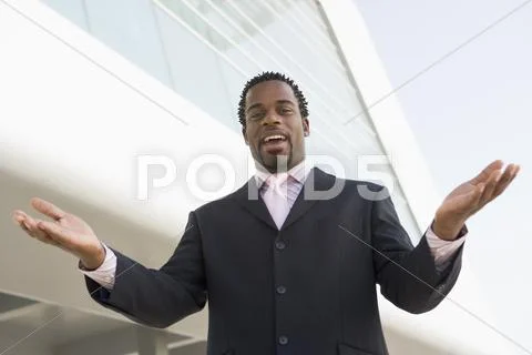 Businessman standing outdoors by building with hands out smiling Stock Photos
