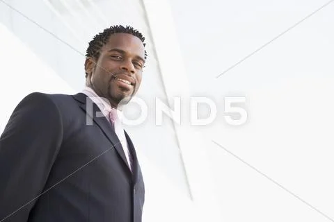 Businessman standing outdoors by building smiling Stock Photos