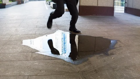 Businessman stepping over a puddle Stock Footage 104070676