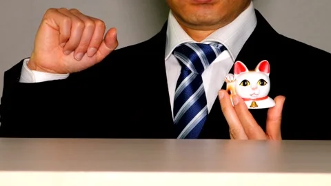 A businessman striking the same pose as a beckoning cat. Video stock 335082290